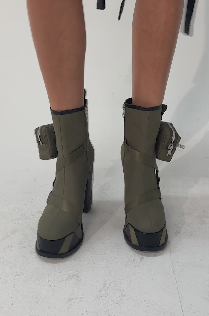 A video of a person wearing AZALEA WANG MAHOMES OLIVE SPORTY COMBAT BLOCK BOOTIE ankle boots, shown from knees down. 