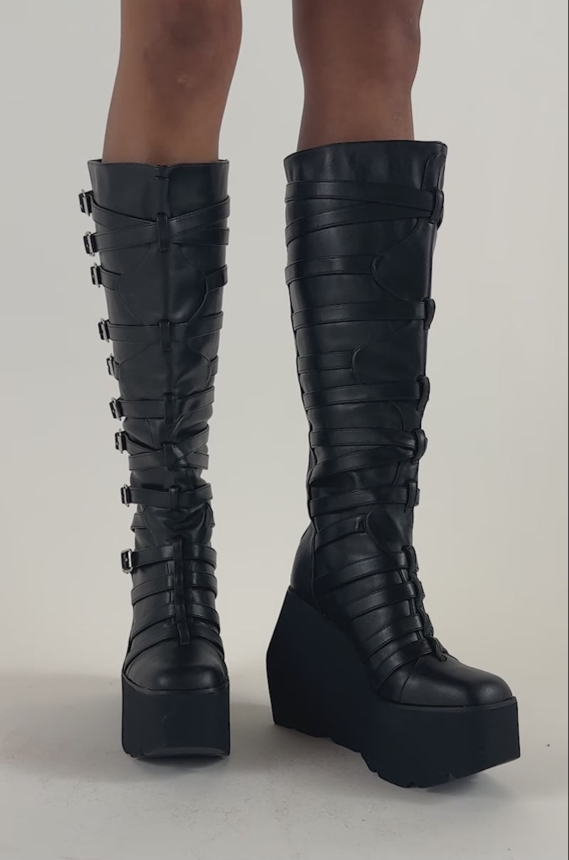 Video of a woman modeling the AKIRA GOLD STATIC BLACK PLATFORM WEDGE BOOT.