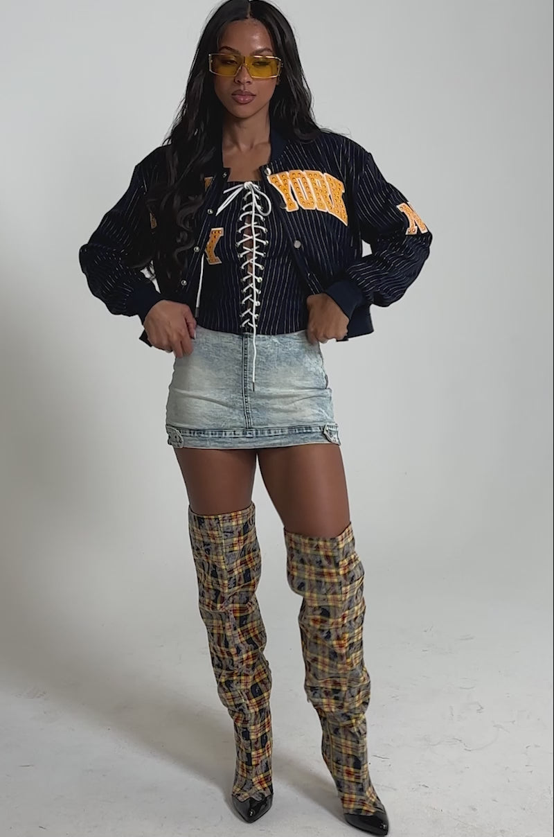 Video of woman modeling the BABY GIRL DENIM MINI SKORT, and yellow plaid thigh-high boots