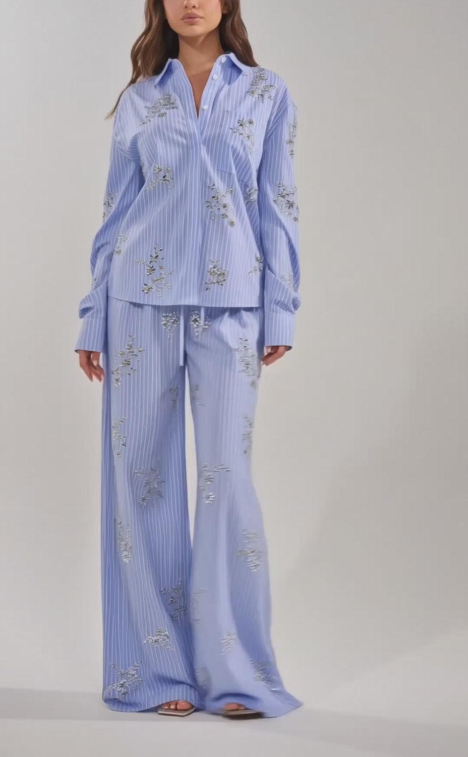 A video of a woman in the SWEET DREAMS RHINESTONE POPLIN BUTTONDOWN, a light blue striped shirt with rhinestone details. 