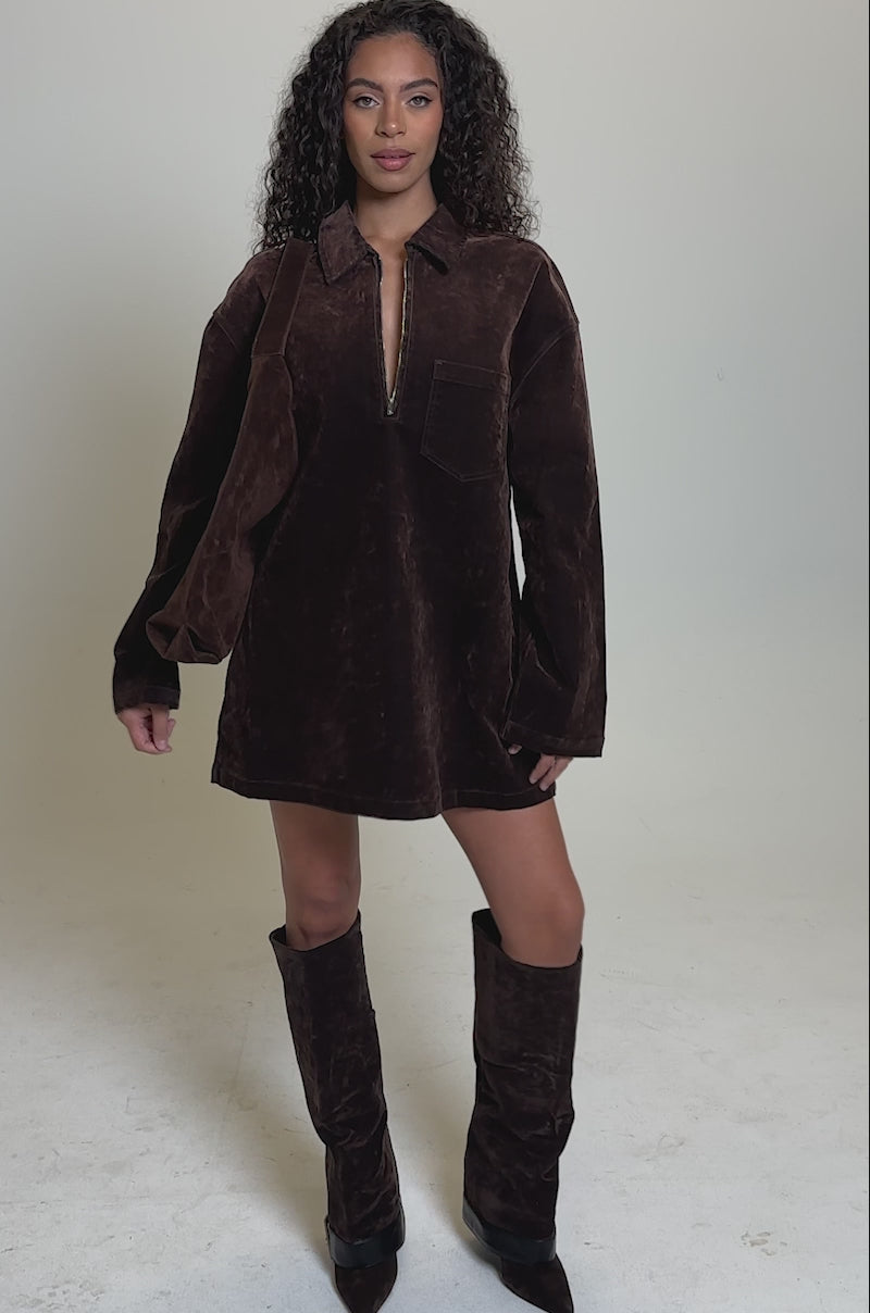 Video of woman modeling the COOL GIRL OVERSIZED VELVET DENIM SHIRT DRESS in chocolate brown, pairing it with matching knee-high boots and a brown bag against a plain, light background.