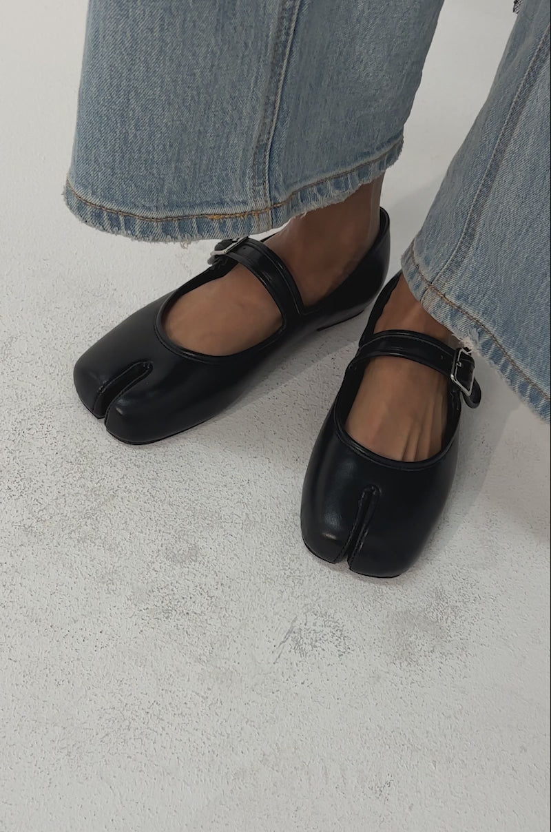 Video of woman modeling the AKIRA GOLD SANG BLACK PU SPLIT TOE FLAT with comfort cushion insoles.