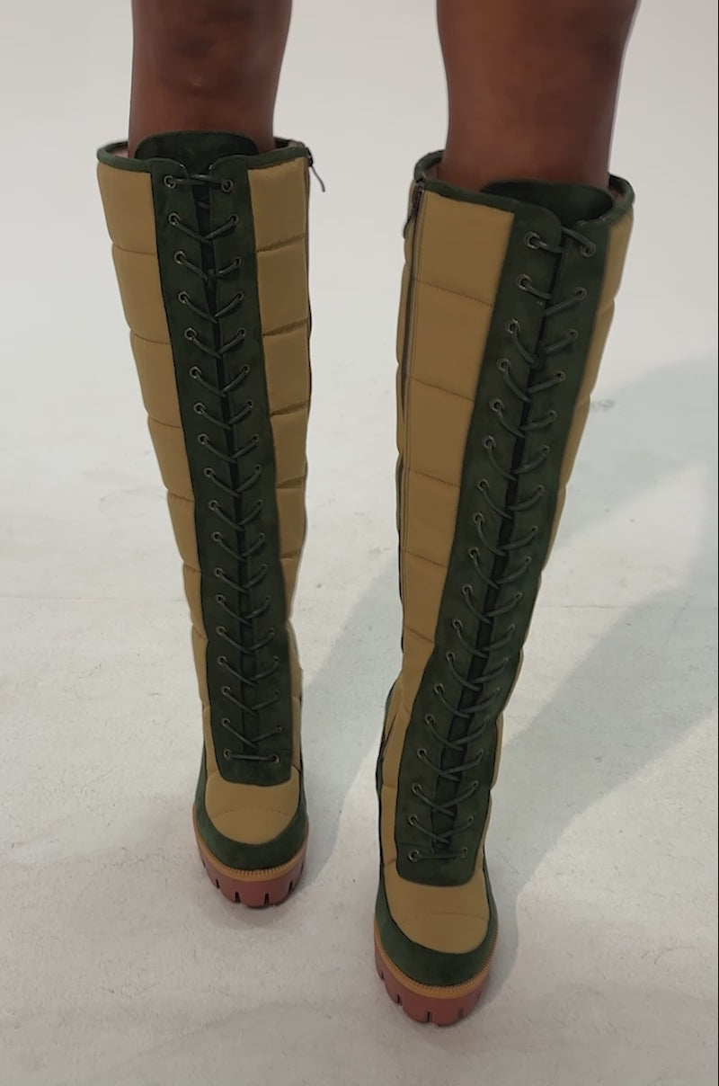 Video of a woman modeling the AZALEA WANG NADINE GREEN MULTI PUFFER BLOCK HEEL BOOT, highlighting the boot’s tan and green design with stylish lace-up details, green suede trim, and convenient zippers.