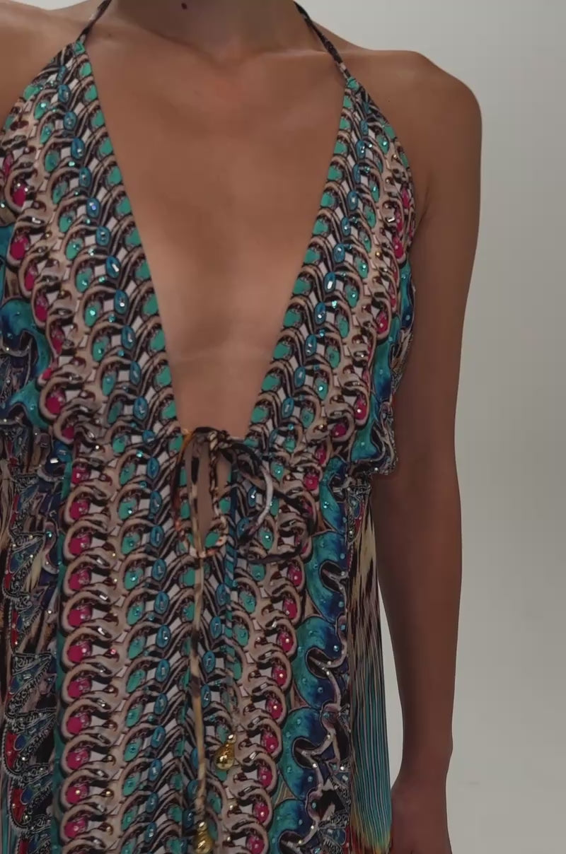 Video of a woman modeling the TALK OF THE TOWN PRINTED MAXI DRESS, featuring a colorful pattern, deep V neckline, and high slit, paired with strappy heels.
