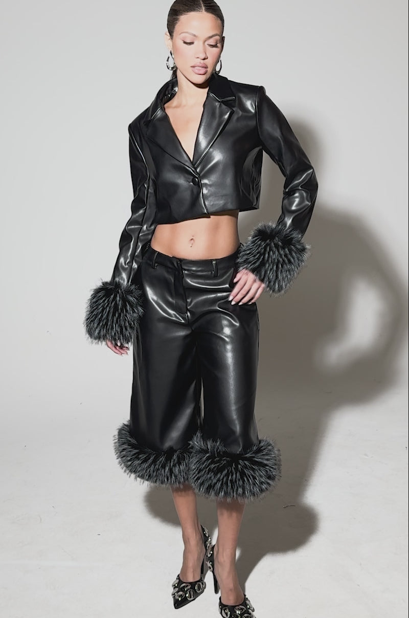 Video of woman modeling the MIND YOUR OWN FUR TRIM BERMUDA SHORTS, featuring a tailored waistband and black-and-white faux fur trim, paired with a matching faux fur cuffed jacket and pointed metallic shoes.