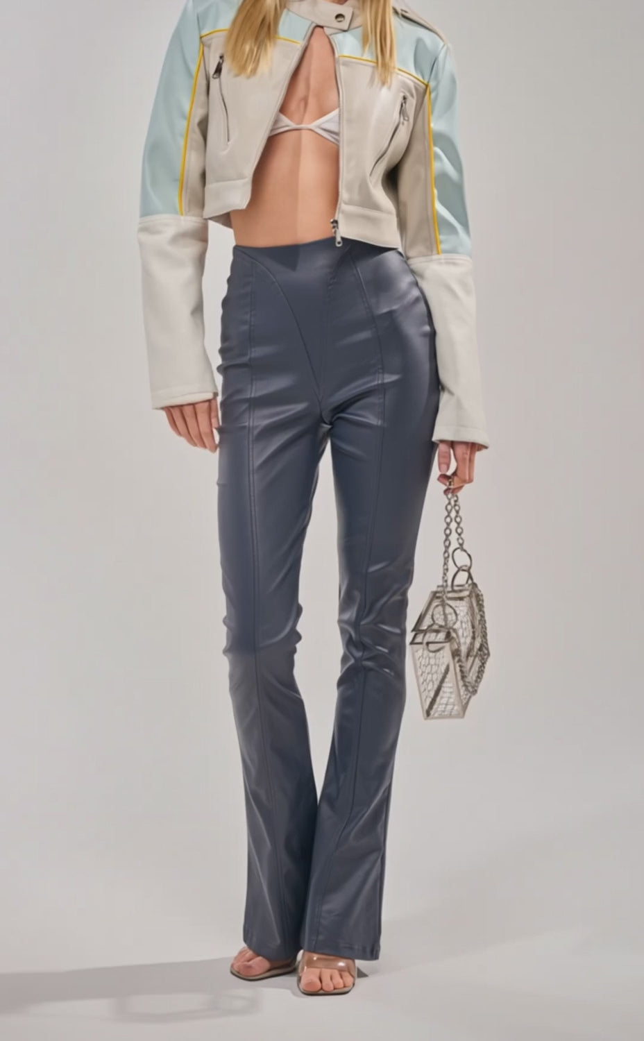 Video of woman modeling the BIG CITY LIVIN FAUX LEATHER LEGGING IN NAVY, heeled sandals, and holding a silver mesh handbag against a plain background.