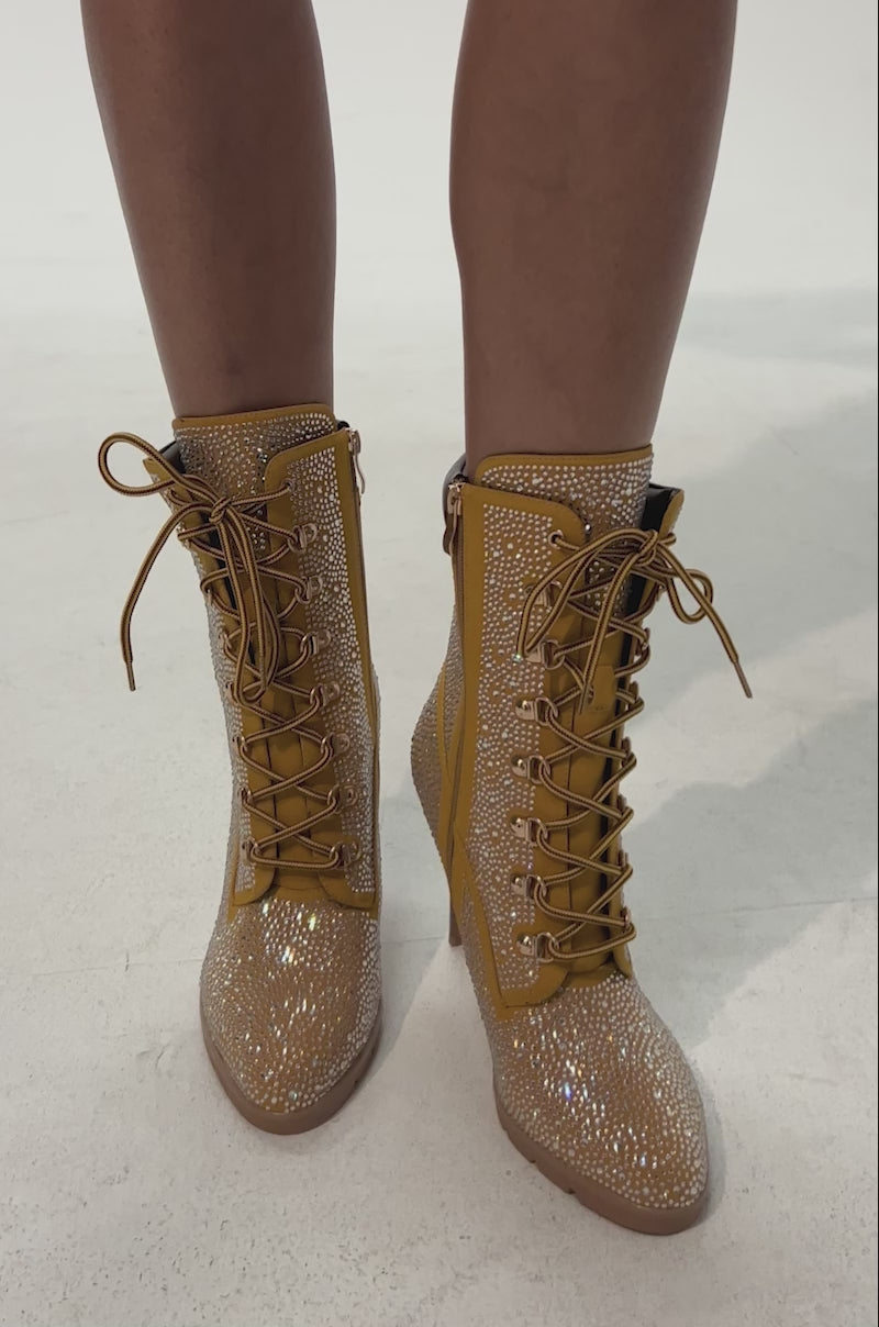 Video of woman modeling the AKIRA GOLD GLAMOUR TAN RHINESTONE BOOTIE—tan faux leather booties with sparkling rhinestones, brown accents, and pointed toes for a dazzling stiletto look.