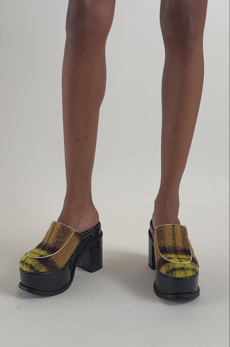 Video of a woman modeling the AKIRA GOLD KATRIEL PLAID MULTI SLIP ON BLOCK PUMP, featuring colorful plaid uppers and black block heels.