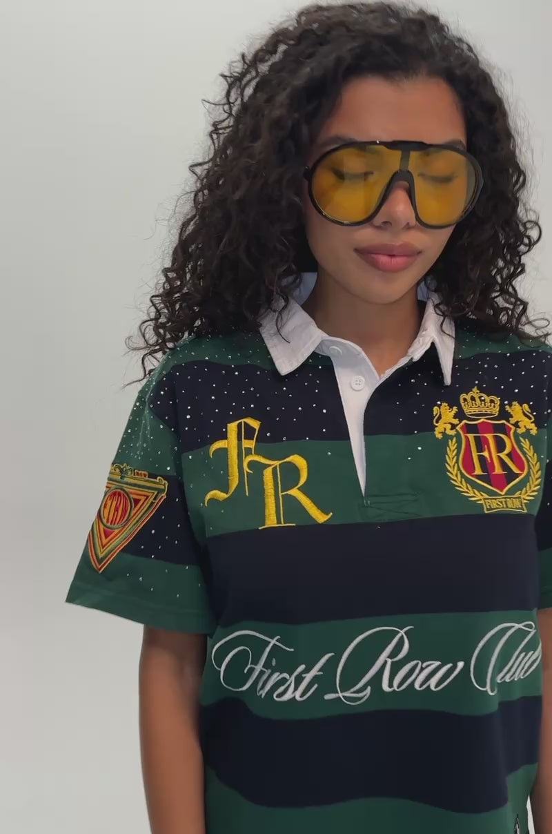 Video of a woman modeling the FIRST ROW ELITE MEMBER CROPPED STRIPED POLO, a green streetwear rugby shirt featuring embroidered crests and “First Row Club” text.