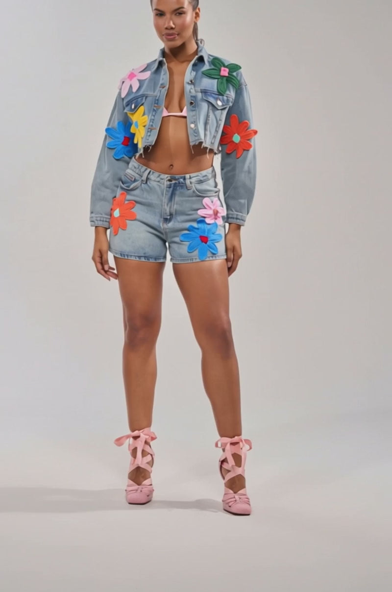 Video of woman modeling the FLOWER PATCH DENIM SHORT with a jacket featuring bold floral appliques, styled with a white crop top 