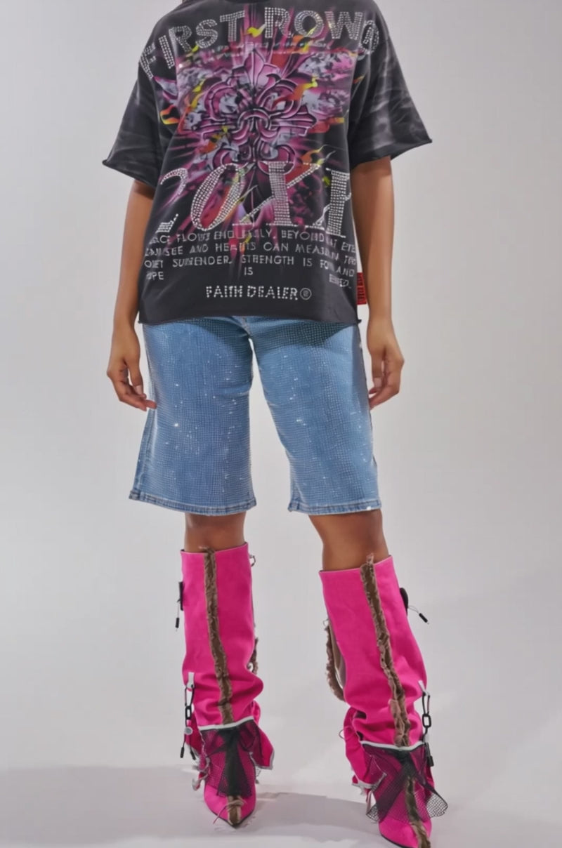 A video of a woman wearing a black graphic oversized t-shirt, BLING BLING RHINESTONE DARK BLUE DENIM BERMUDA SHORT, and bright pink knee-high boots with black mesh details.