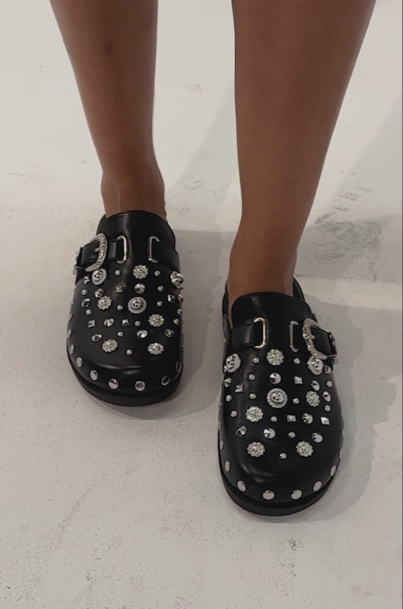 Video of a woman modeling the AZALEA WANG MAULDIN HARDWARE EMBELLISHED CLOG IN BLACK, adorned with silver studs and rhinestones of varying sizes.