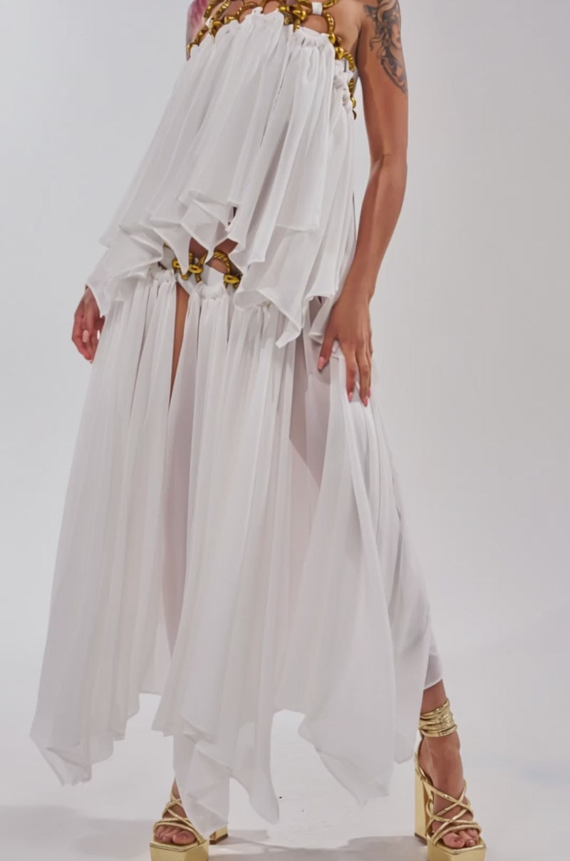 Video of woman modeling the DESERT VIBES MIDI SKIRT, a white chiffon skirt paired with gold platform heels and a flowing gold chain skirt featuring high slits