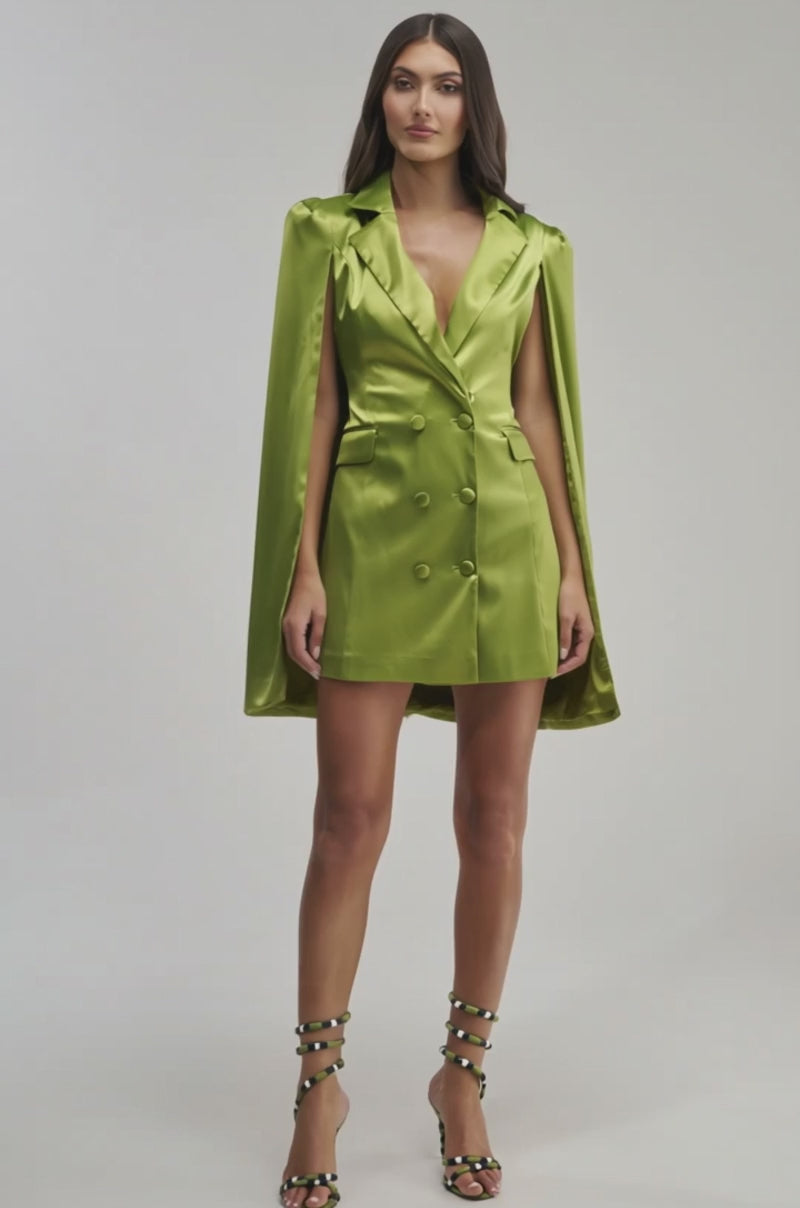 A video of a woman in the IMANI Cape Sleeve Blazer Dress in Green, featuring a deep V-neck and double-breasted buttons.