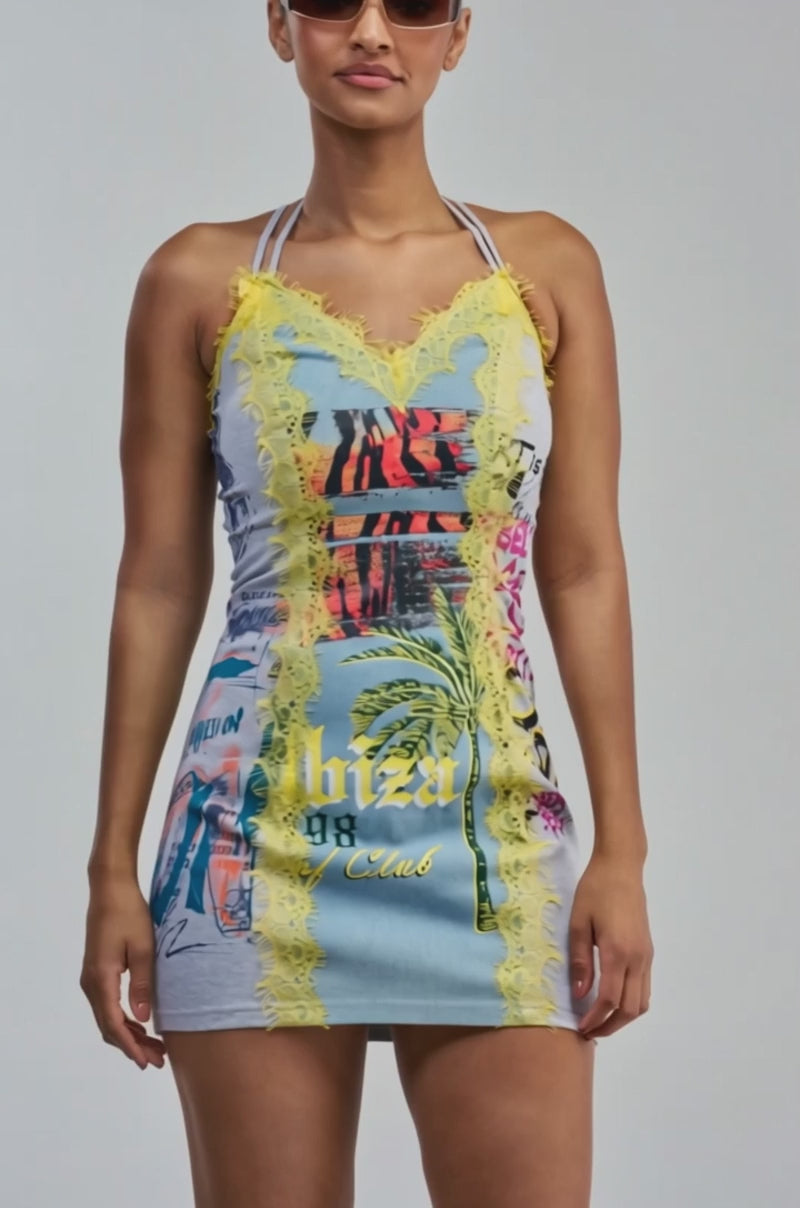 Video of a woman modeling the JUST BETWEEN US MINI DRESS YELLOW MULTI— a sleeveless, fitted streetwear mini dress featuring multicolored graphics and yellow lace trim.