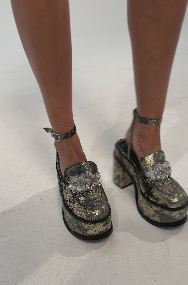A video of a person wearing the AZALEA WANG CARNEGIE GREEN MULTI BROCADE PLATFORM BLOCK HEEL STRAP PUMP, featuring chunky block heels and ankle straps. 