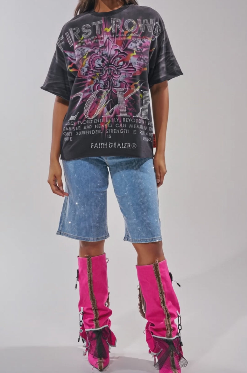 A video of a woman in the 20XX RHINESTONE CANVAS T-SHIRT, knee-length blue denim shorts, and bright pink knee-high boots with black laces and decorative accents.