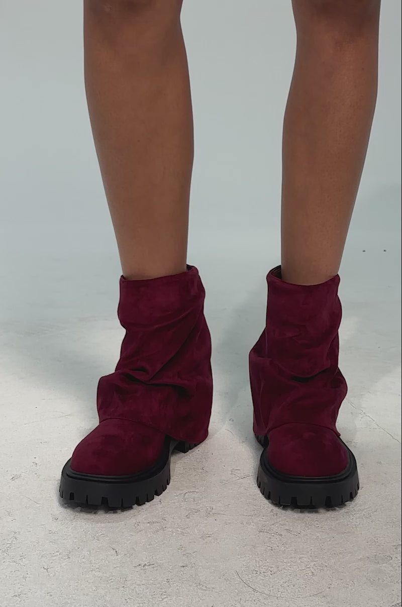 A video of a model wearing the AZALEA WANG CLARKE FAUX SUEDE BURGUNDY FLAT BOOTIE which features a burgundy faux suede design with a slouchy, foldover shaft and chunky lug heel.