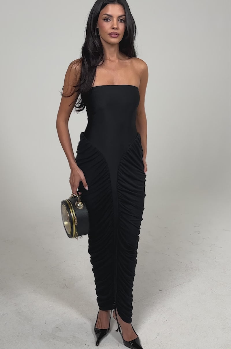 Video of woman modeling the SEASON OF SLAY STRAPLESS MAXI DRESS with ruched skirt panels, accessorized with a small round black handbag and black pointed heels