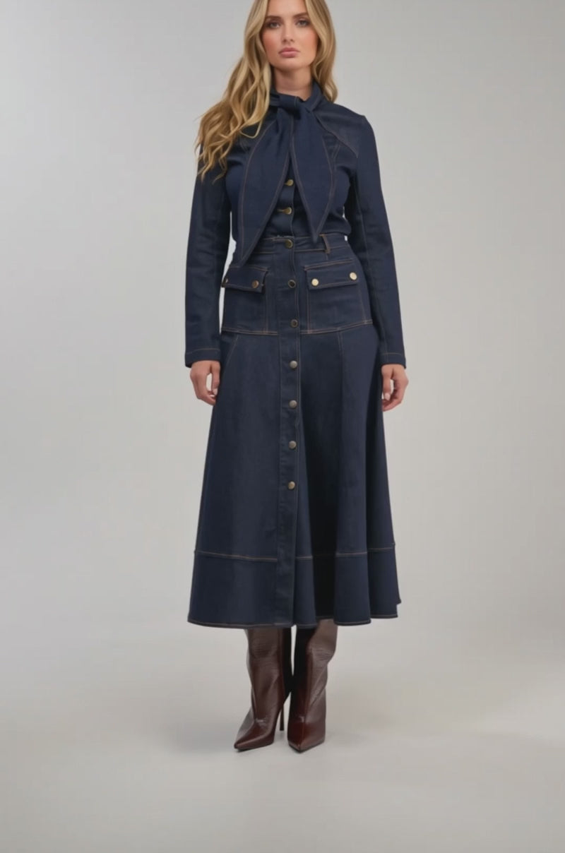 Video of a woman modeling the OUTLAW A-LINE DENIM MIDI SKIRT in a matching dark wash, and knee-high brown boots.