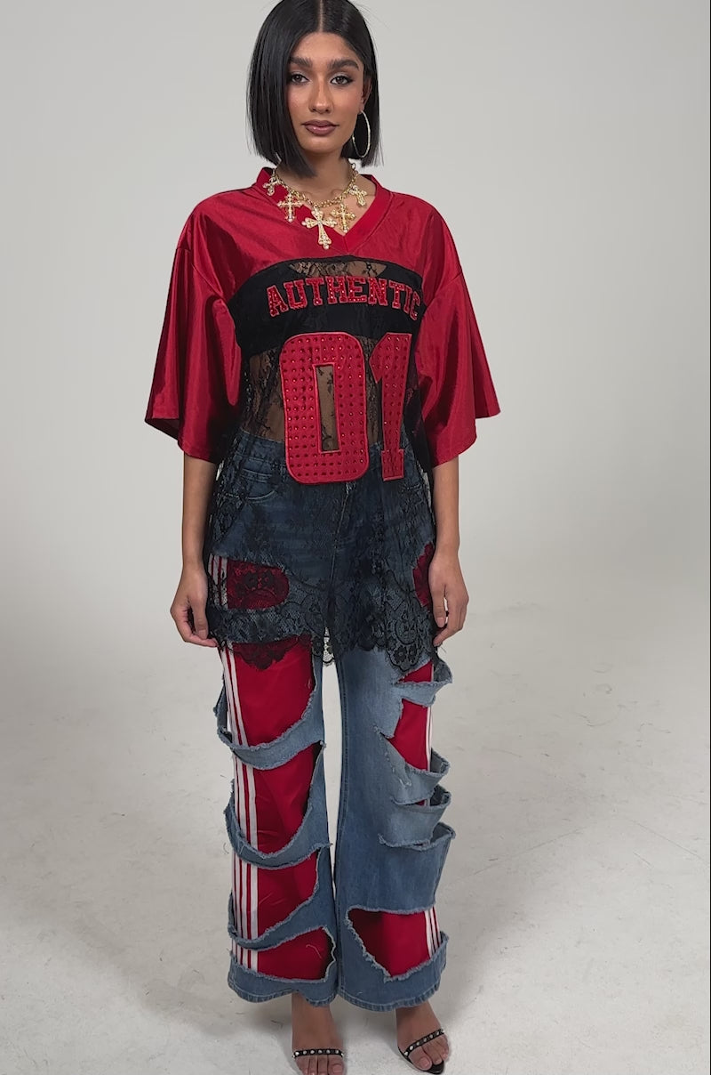 Video of woman modeling the LEXIE LOW RISE DENIM TRACK PANT—distressed blue jeans with white-striped track pants beneath—styled with black high-heeled sandals