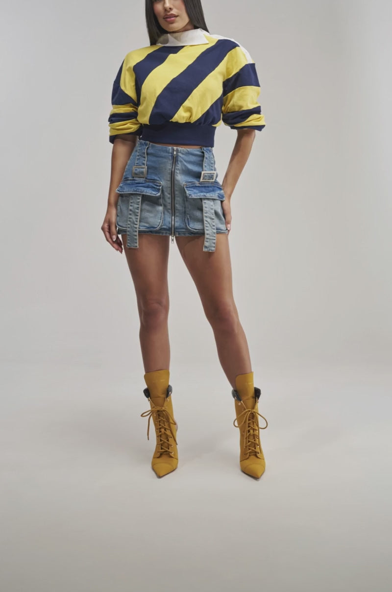 Video of woman modeling the MARY DENIM MINI SKIRT—a blue denim mini skirt featuring large cargo pockets and zippers