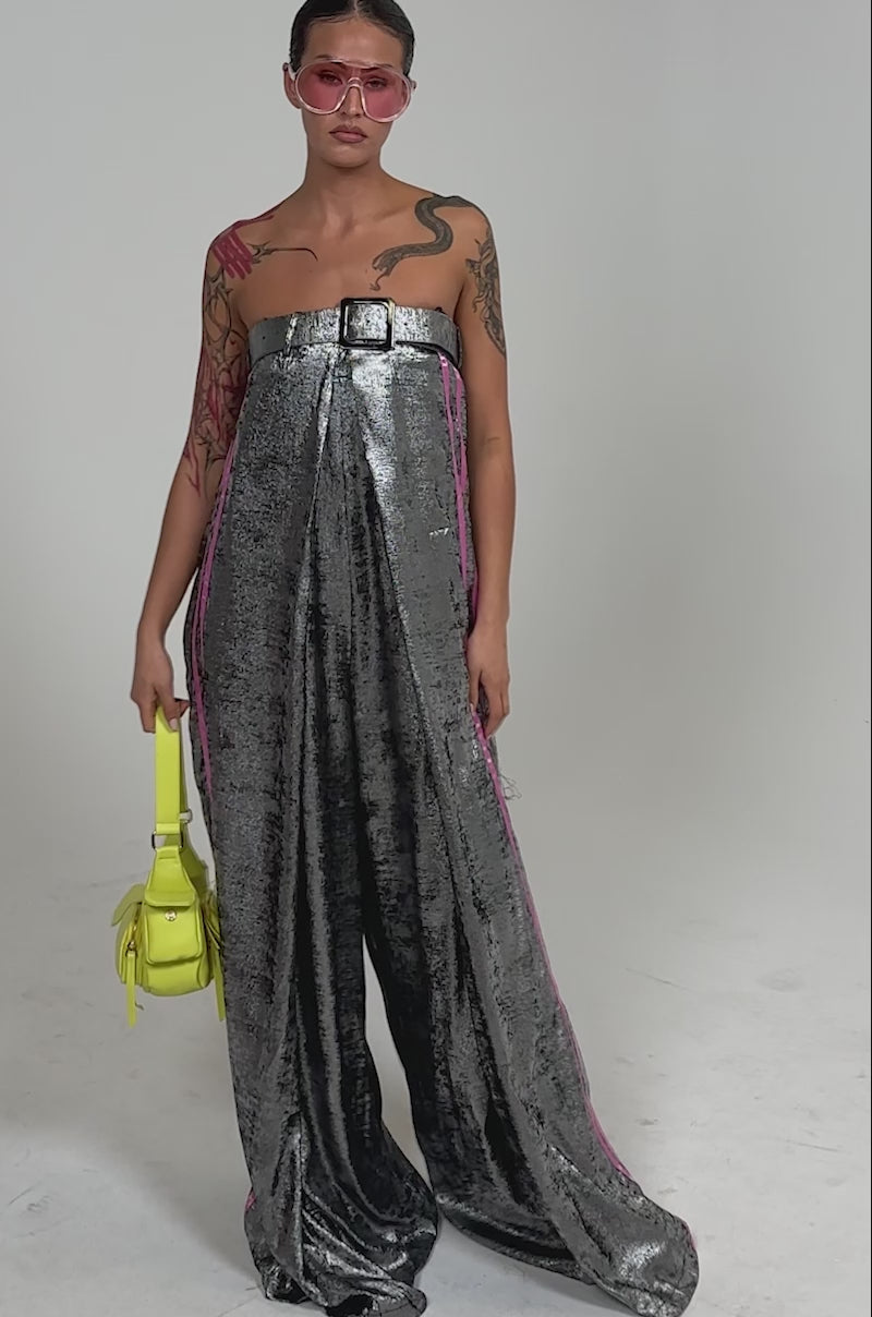 Video of woman modeling the RUN THE SHOW METALLIC JUMPSUIT—a strapless, wide-leg piece featuring a square neckline detail.