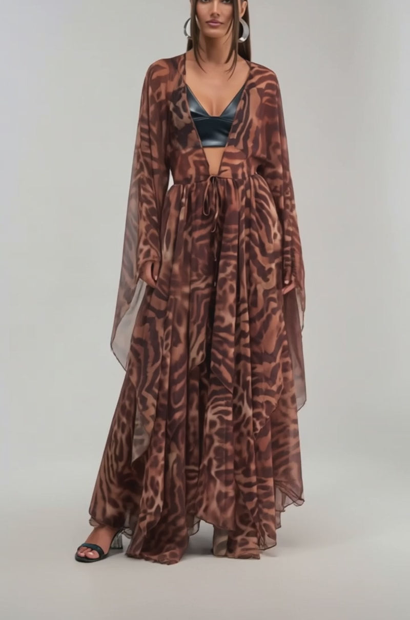 A video of a woman wearing the MOONLIGHT TIGER DUSTER—a sheer, flowing tiger print chiffon piece—over a black bralette.