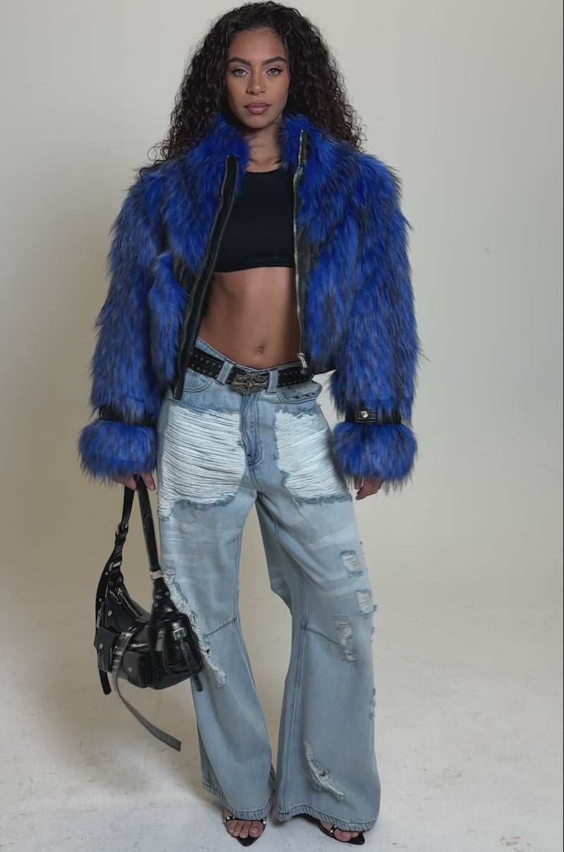 Video of woman modeling the ASTRO FUR PANEL MOTO, an electric blue faux fur jacket, over distressed light-wash patchwork jeans, standing against a plain background.