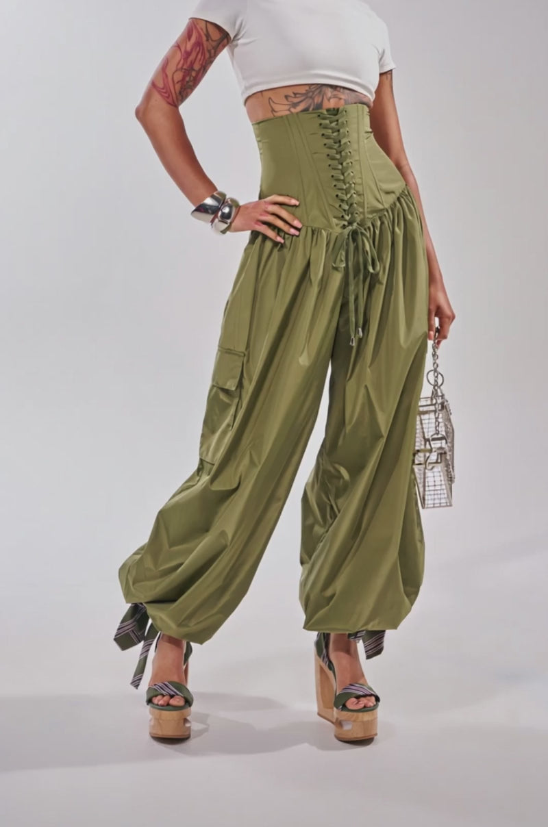 Video of woman modeling the LOCKED UP FOR GOOD LACE UP BALLOON PANT, styled with platform heels, a metallic purse, bold jewelry, and showing off her arm tattoos.