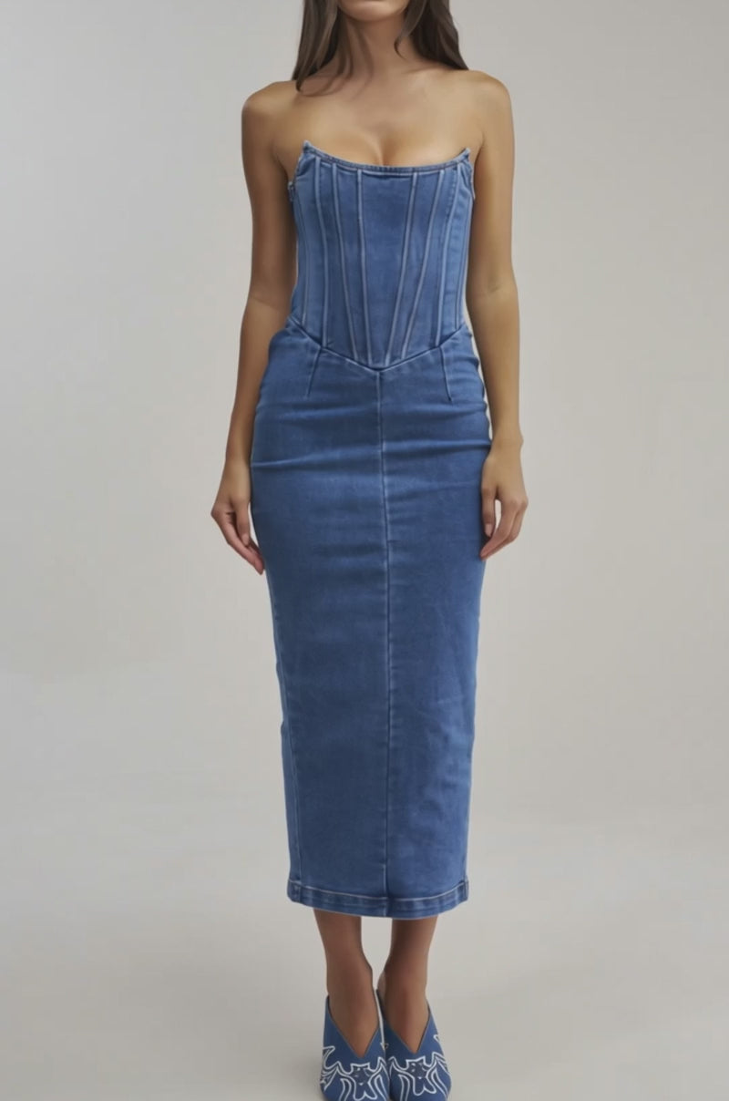 A video of a woman wearing the DAYDREAM IN DENIM STRAPLESS MAXI DRESS, a fitted, bodycon maxi with visible seams and a stylish lace-up back.