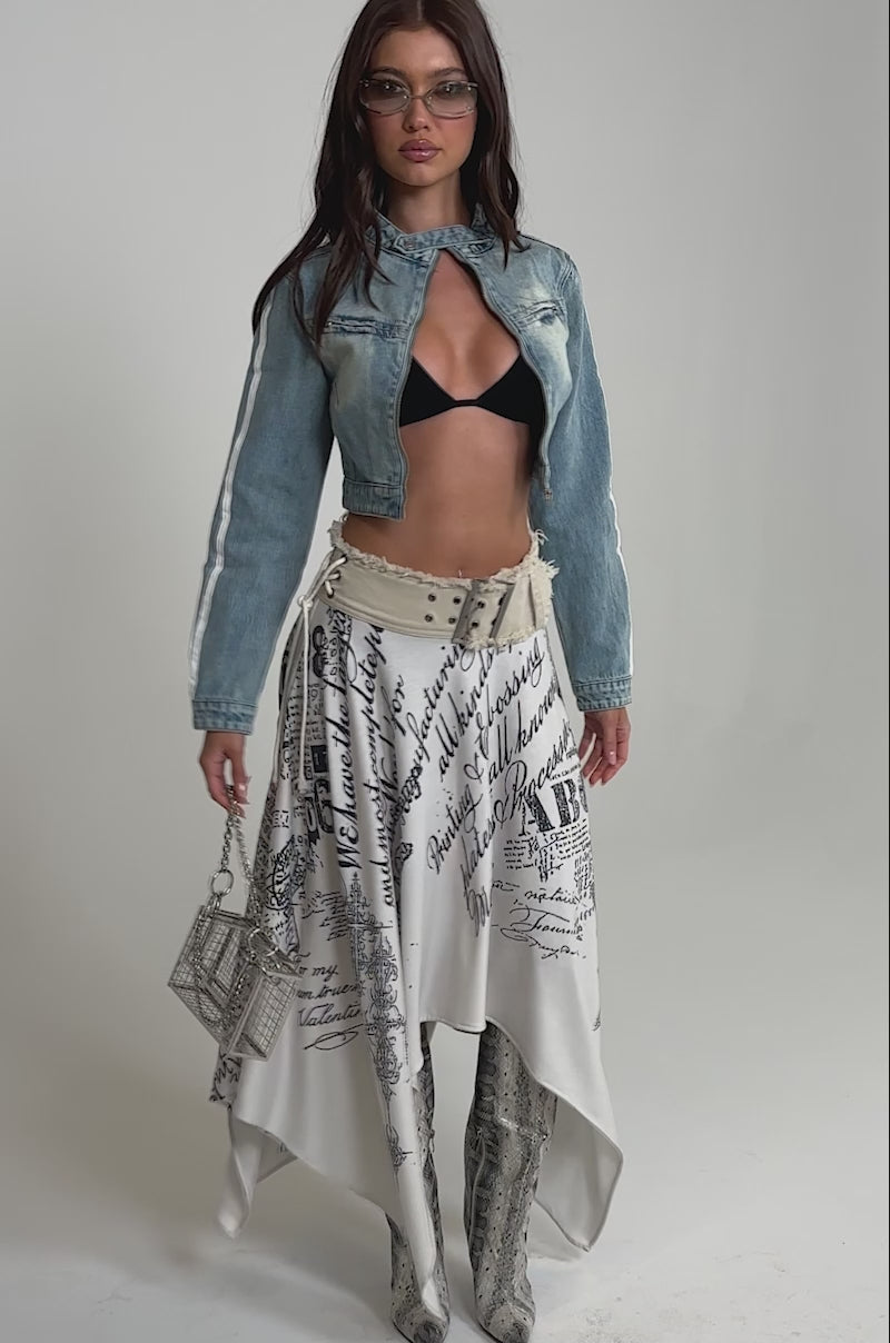 Video of woman modeling the AFTER HOURS DENIM MOTO IN LIGHT BLUE jacket, with one hand on her hip and the other on her belt.