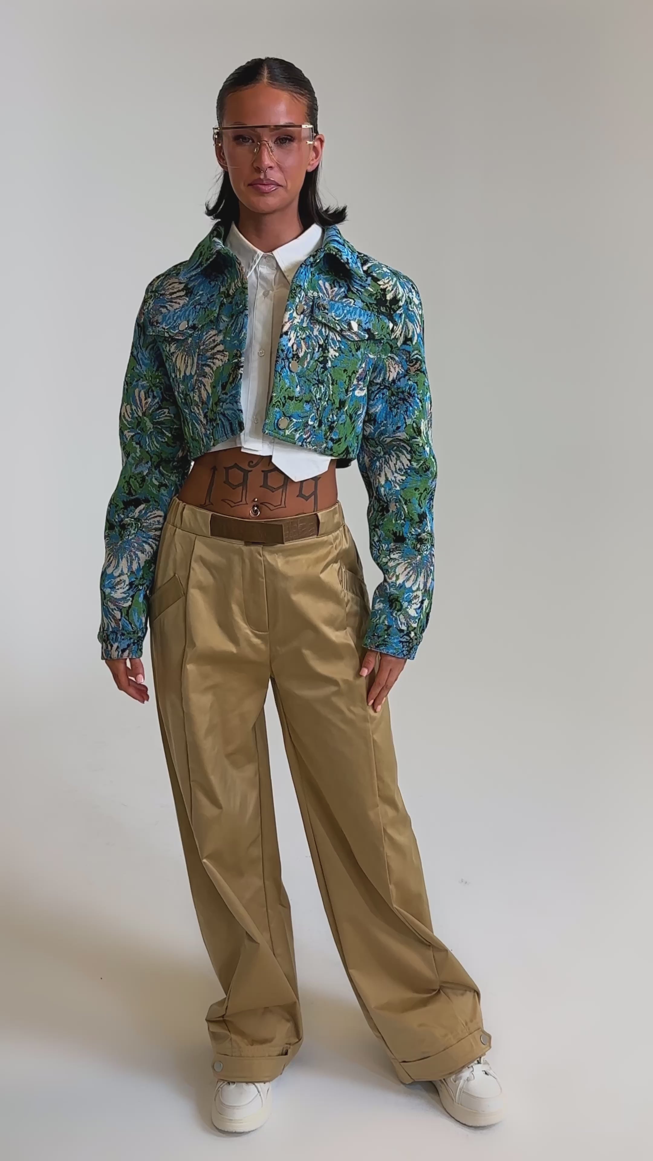 A video of a model wearing a blue floral cropped jacket, white shirt, and the COOLEST ON THE BLOCK TROUSER with a wide-leg silhouette.