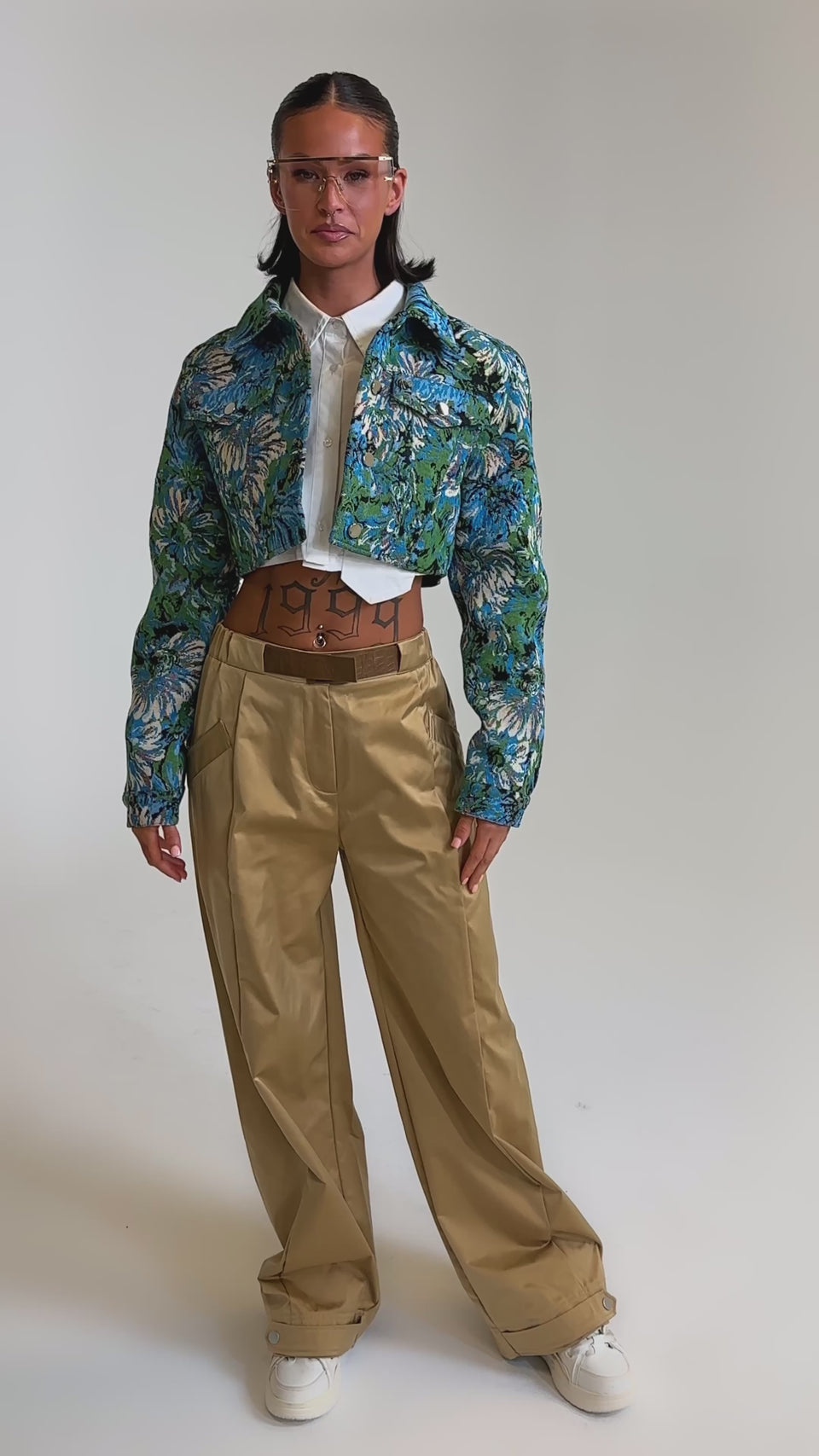 A video of a model wearing a blue floral cropped jacket, white shirt, and the COOLEST ON THE BLOCK TROUSER with a wide-leg silhouette.