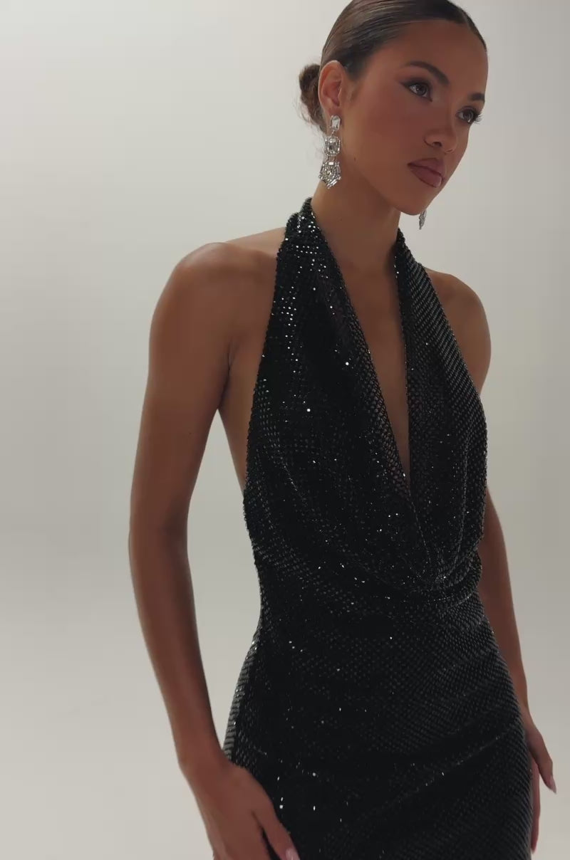 Video of woman modeling the THE GLOW UP HALTER RHINESTONE MINI DRESS IN BLACK—a sleeveless dress featuring a halter neckline and shimmering rhinestone details.