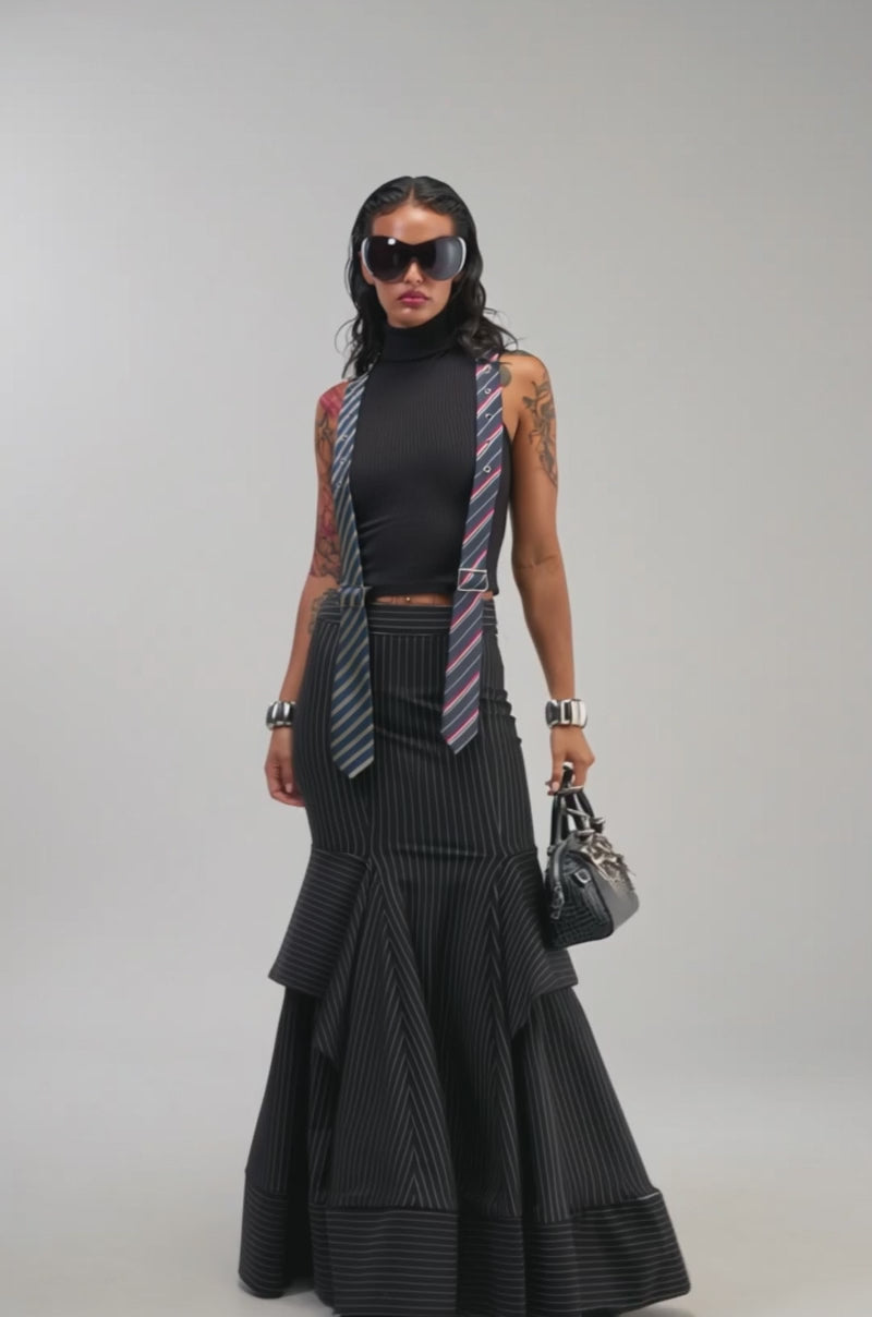 Video of a woman modeling the TIED UP SLEEVELESS SWEATER—a black ribbed knit turtleneck.