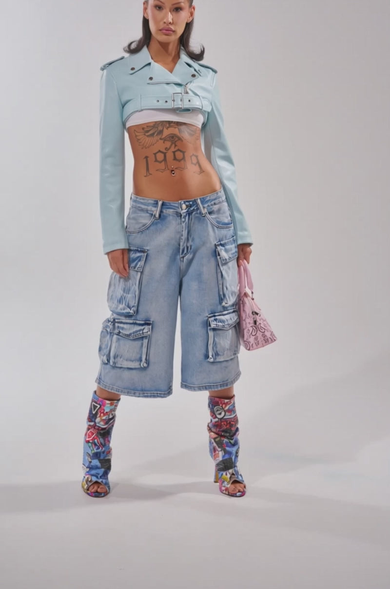 Video of woman modeling the HARLEY LUXE ULTRA CROP MOTO IN LIGHT BLUE, styled over a white crop top and low-rise jeans, showcasing a bold "1999" eagle tattoo on her stomach.