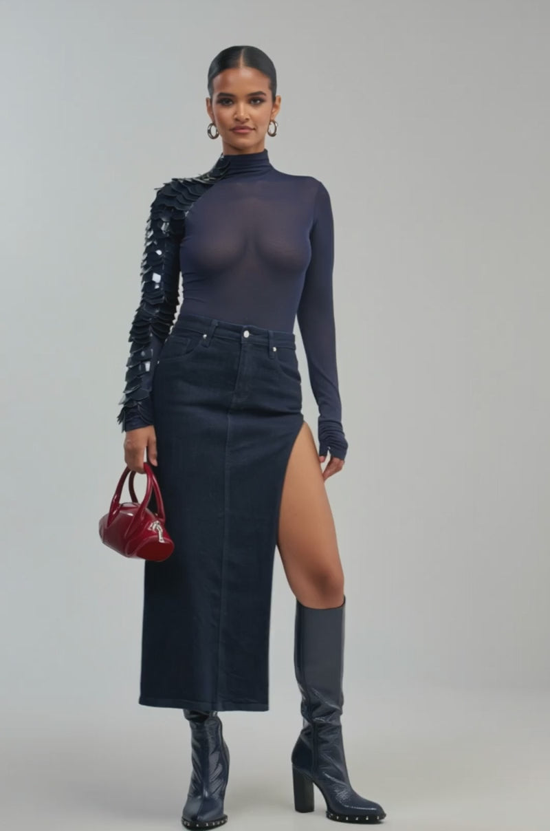 Video of a woman modeling the VELMA VINYL SINGLE SLEEVE SCALE TOP IN NAVY—a navy mesh long sleeve going out top with shiny black embellishments on one sleeve.