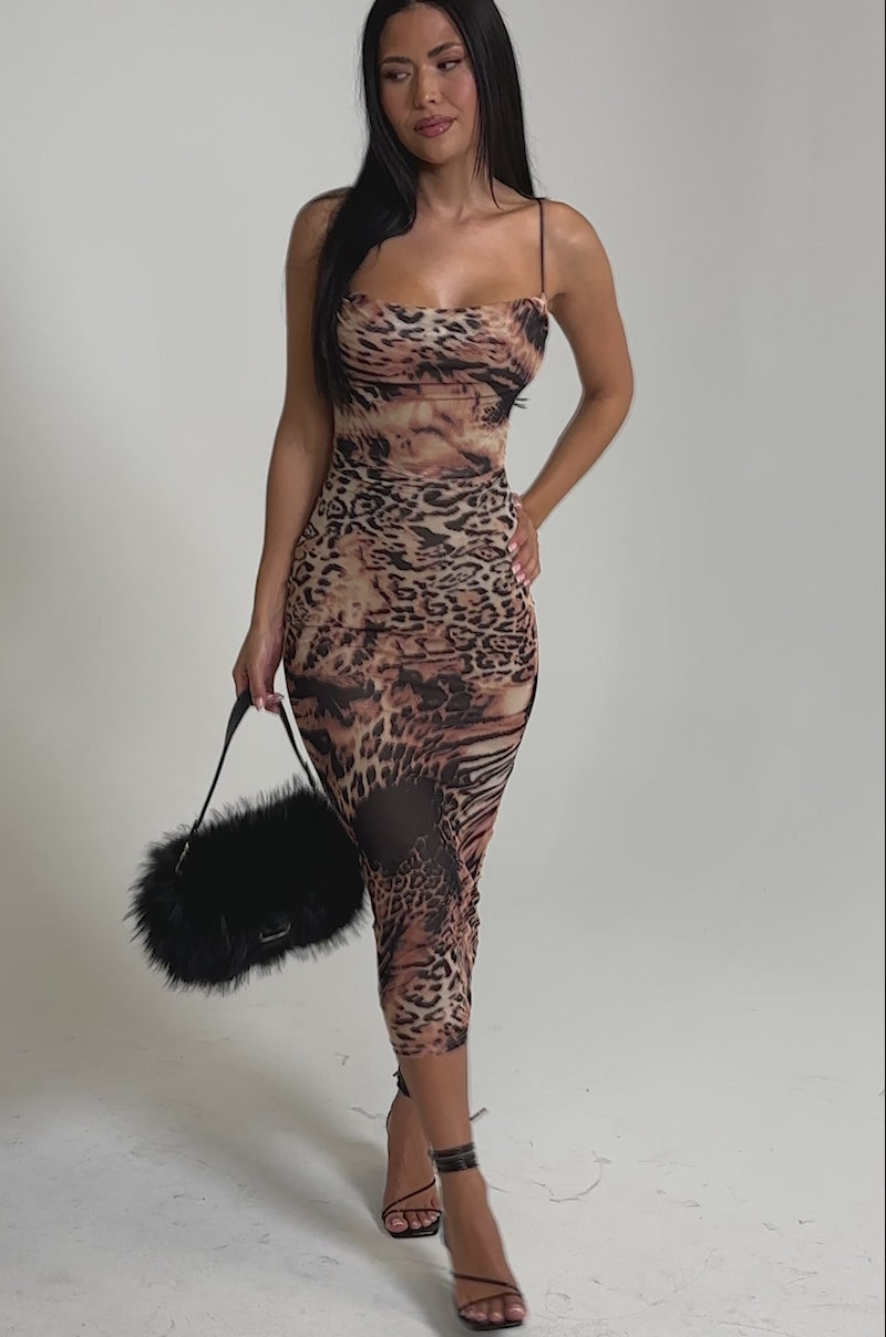 A video of a woman in the CLAWS OUT LEOPARD MIDI SLIP DRESS, posing against a light gray background with a black furry handbag, black strappy heels, and long straight dark hair.