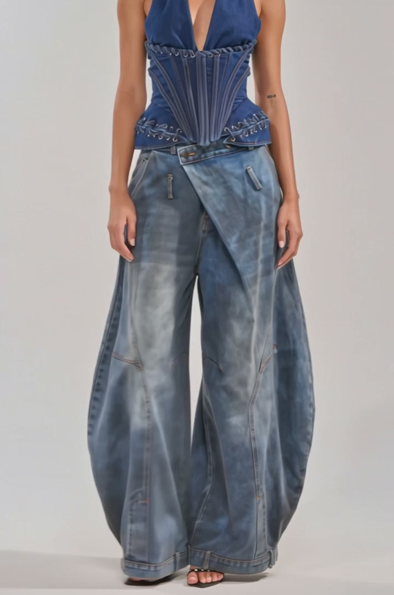 A video of a woman in the NOT MY PROBLEM DENIM CORSET with decorative stitching and wide-leg draped denim jeans poses confidently against a light background.