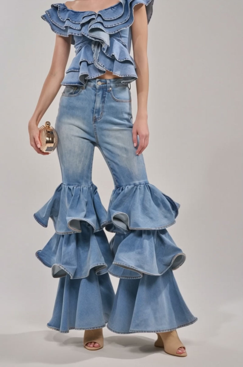 Video of woman modeling the DREAMING BIG DENIM RUFFLE TOP and high-waisted jeans, holding a textured clutch purse.