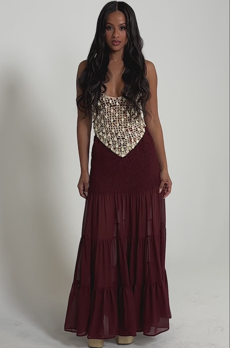 Video of woman modeling the DRIFTING AWAY MAXI SKIRT—a maroon, tiered maxi skirt with sheer layers—paired with platform shoes.