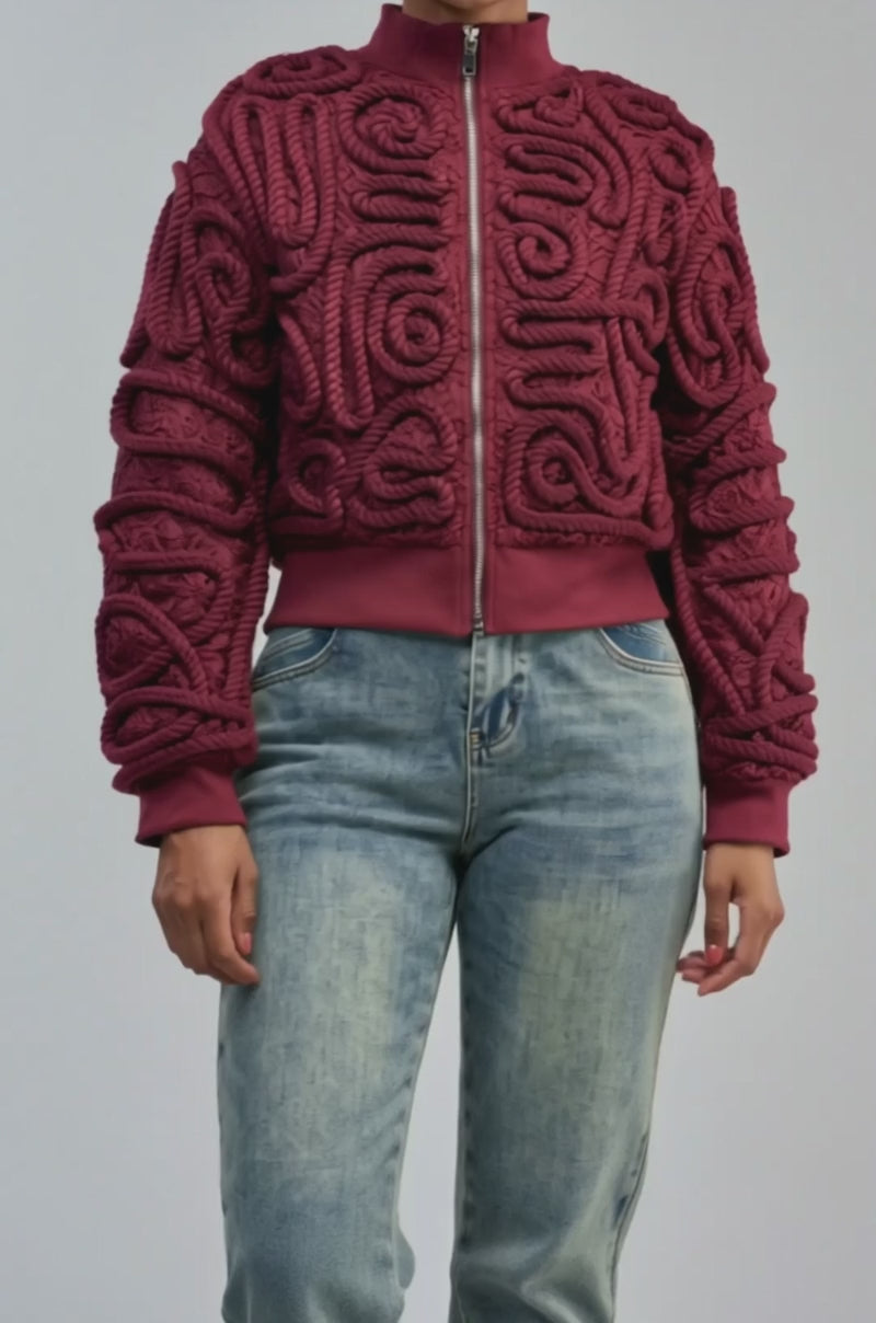 Video of a woman modeling the LOVER GIRL BOMBER—a statement streetwear burgundy lace bomber jacket with rope detail and raised patterns.