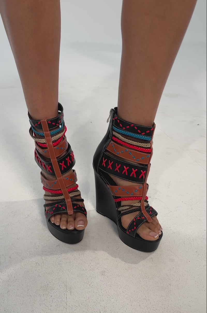 A video of a person in the AZALEA WANG ZINNIA BLACK MULTI WEDGE SANDAL with colorful tribal patterns and a platform sole. 