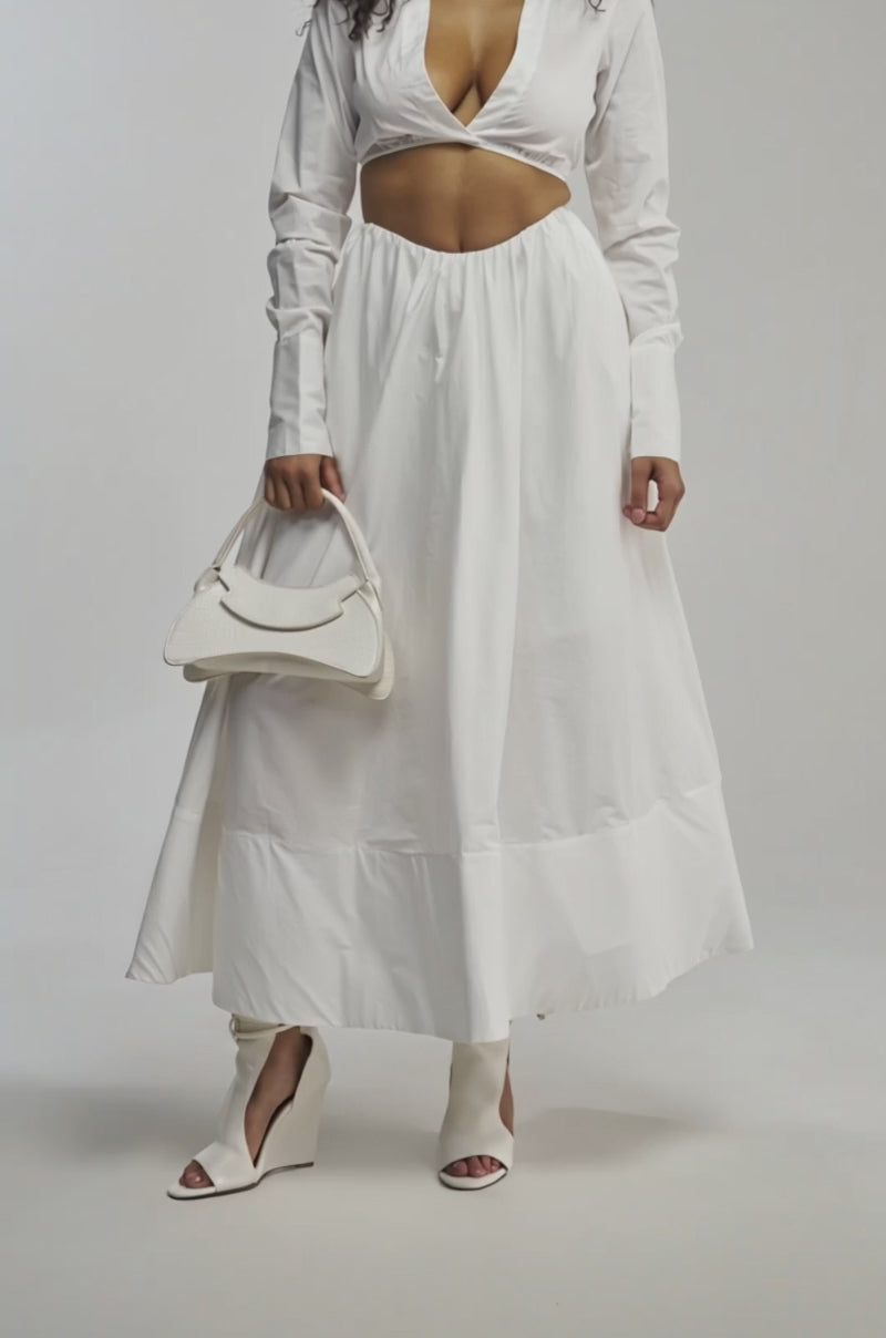 Video of woman modeling the LETS GO PARTY BLOUSE—a white poplin, long-sleeve crop top—paired with a matching skirt 