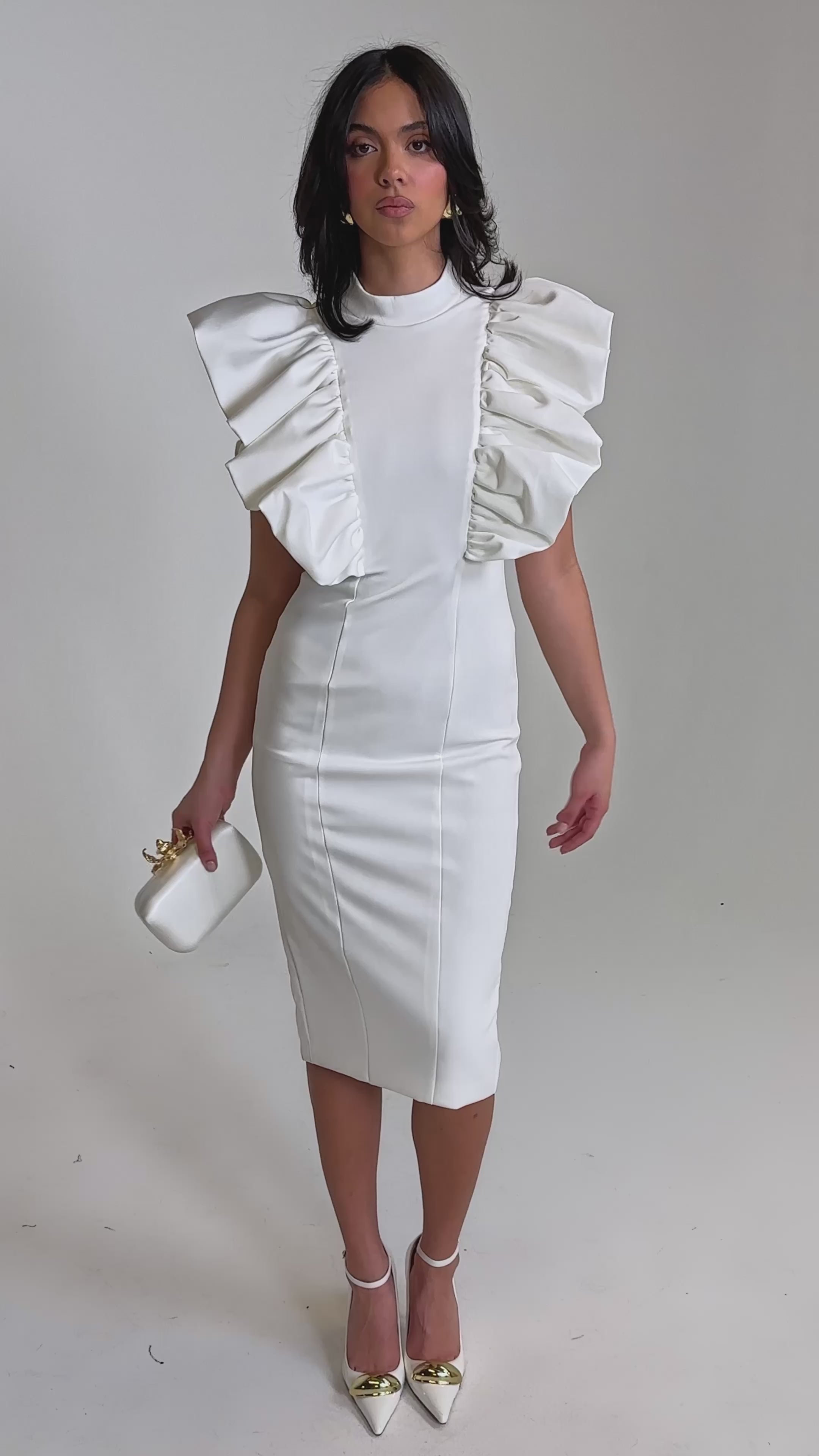 A video of a woman in the TRUTH BE TOLD MIDI DRESS IN WHITE, featuring large ruffled sleeves. 