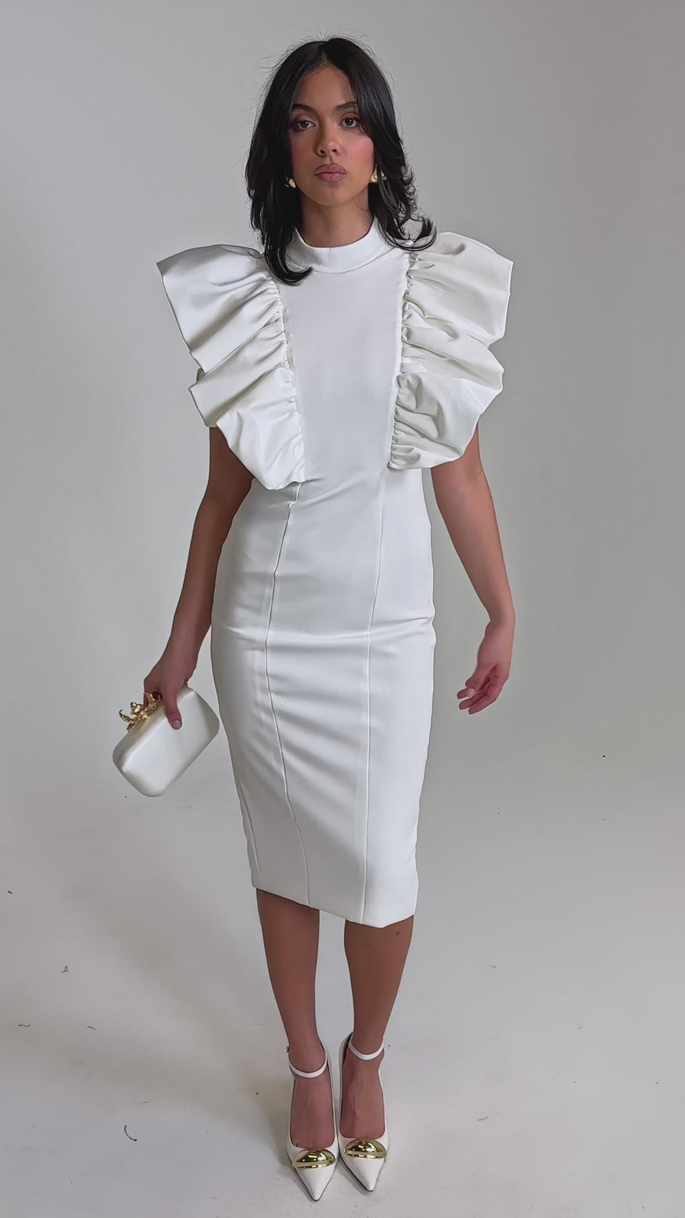 A video of a woman in the TRUTH BE TOLD MIDI DRESS IN WHITE, featuring large ruffled sleeves. 