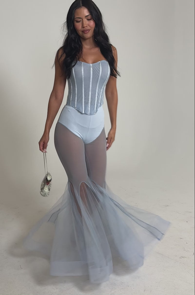 Video of woman modeling the FEELING BLUE MESH FLARE PANT—high-waisted blue sheer mesh flares with solid briefs underneath and open-toe heels—this look features a subtle mermaid-inspired silhouette against a plain white backdrop.