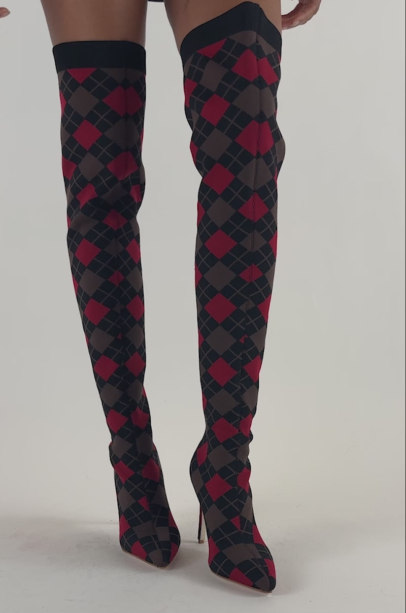 Video of a woman modeling the AZALEA WANG ARGYLE BROWN MULTI STRETCH STILETTO BOOT, featuring an over-the-knee design with a bold red and black diamond pattern.