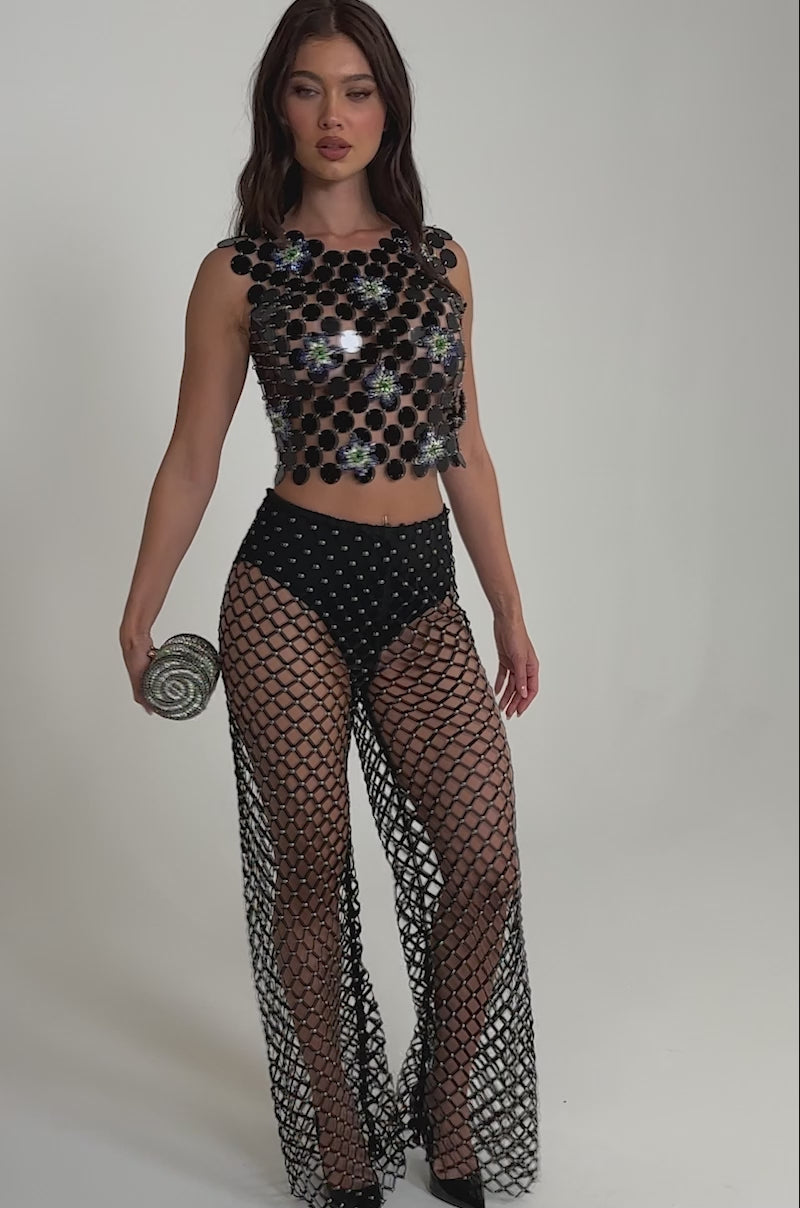 A video of a woman in the KARISSA SEQUIN CHAIN TOP, paired with high-waisted mesh pants over black briefs. S